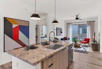 A modern kitchen with a granite countertop and a large abstract painting above it.at Marketside Villas at Verrado, Buckeye, AZ 